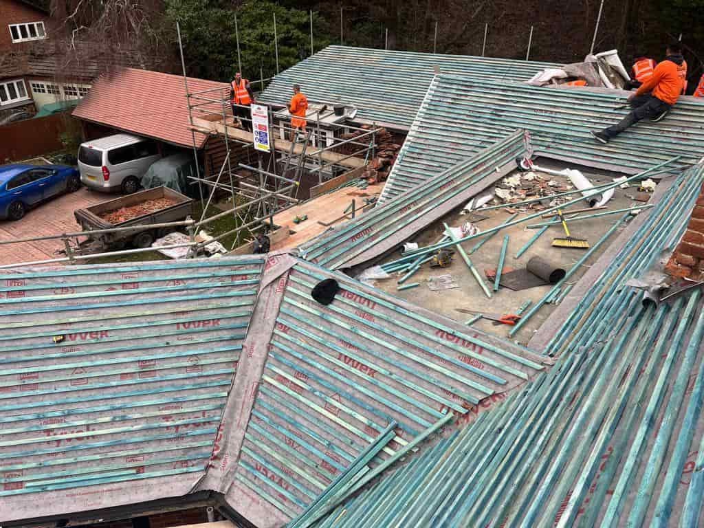 This is a photo of a large re-roof being carried out by TVB Roofing Wellingborough, there are multiple sections of pitched roofs adjoining to a central flat roof